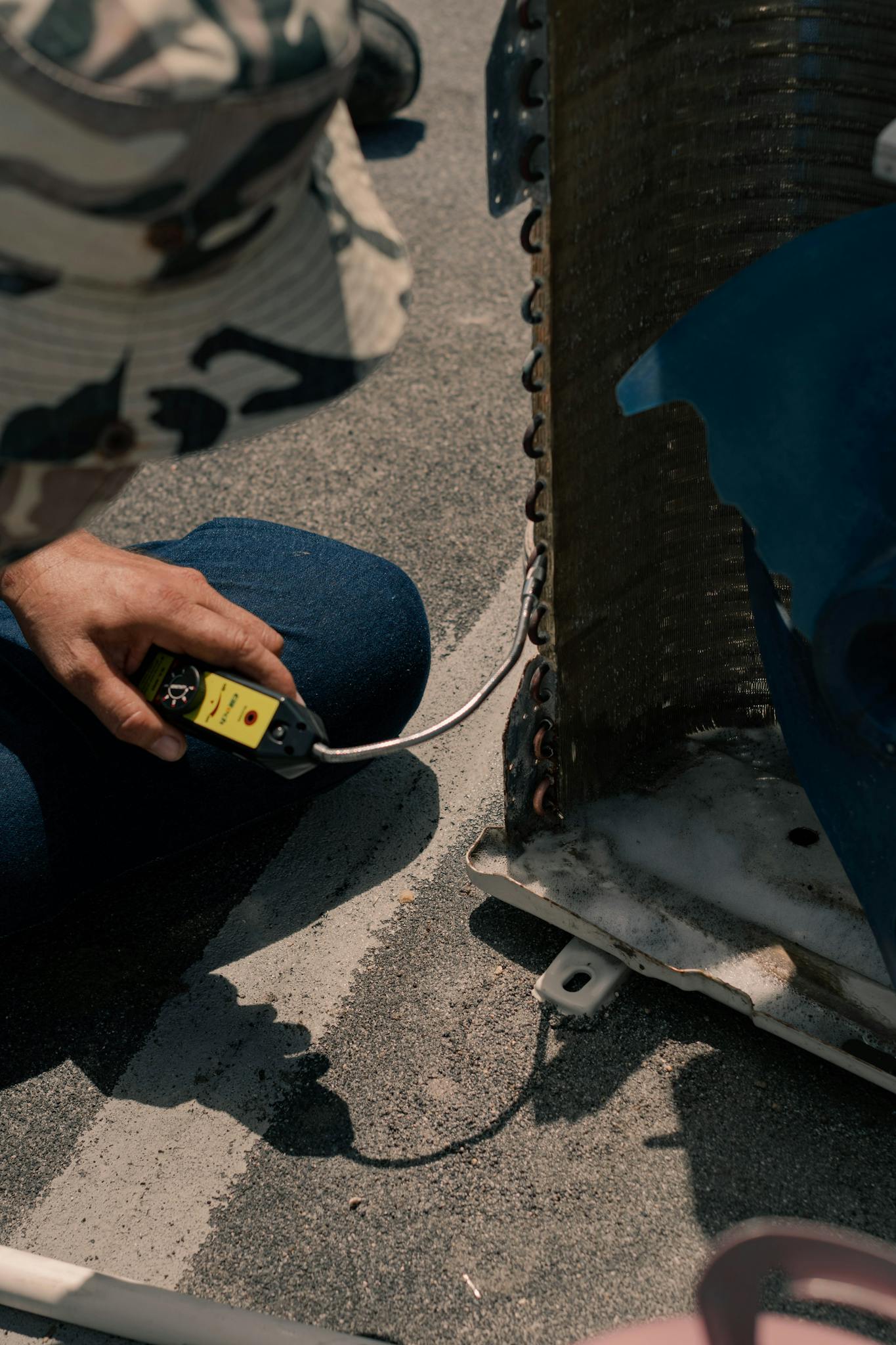 Close-up of a technician working on an air conditioning unit with tools on a sunny day.
